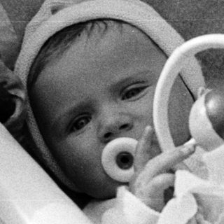 Black and white photo of a baby in a basket.