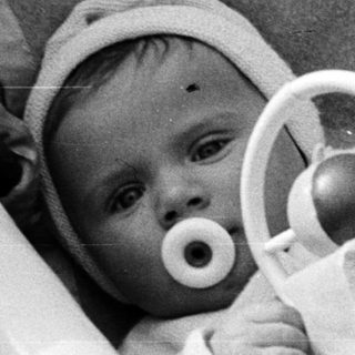Black and white photo of a baby in a crib.