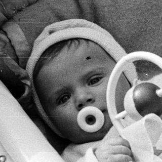 Black and white photo of a baby in a crib.
