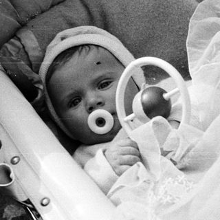 Black and white photo of a baby in a crib.