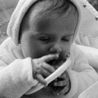 Baby in a stroller, chewing on something, black and white.