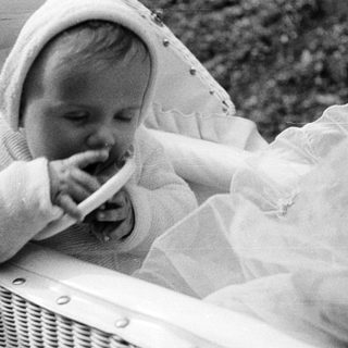 Baby in a stroller, chewing on something, black and white.