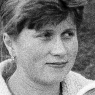 Woman holding a smiling baby outdoors in a black and white photo.