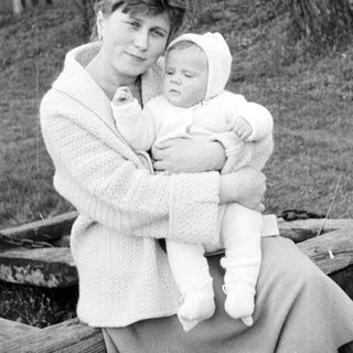 Woman holds baby outdoors in a vintage black and white photo.