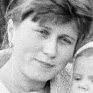 Woman holds baby outdoors in a vintage black and white photo.
