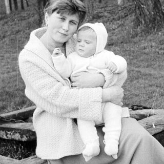 Woman holds baby outdoors in a vintage black and white photo.