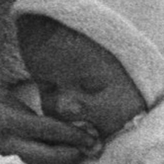 Black and white image of a baby in a vintage pram.