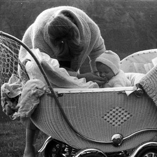 Black and white image of a baby in a vintage pram.
