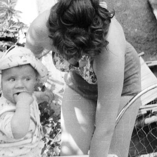 Baby in a hat is being observed by a woman.