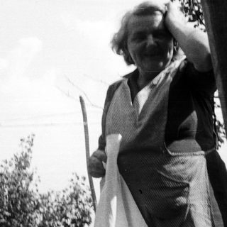 Woman hanging laundry outdoors in a vintage black and white photo.