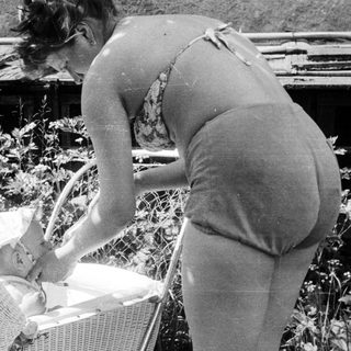Woman tending to a baby in a wicker basket.