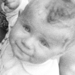 Woman holding a baby outdoors in a black and white photo.