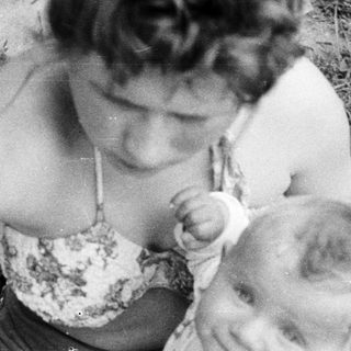Woman holding a baby outdoors in a black and white photo.