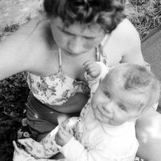 Woman holding a baby outdoors in a black and white photo.