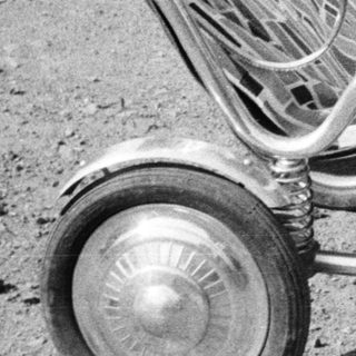 Baby sits in a vintage stroller outdoors.