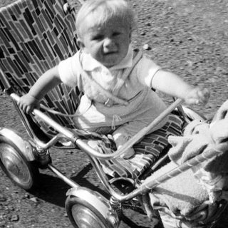 Baby in vintage stroller, captured in black and white.