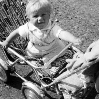 Baby in vintage stroller, captured in black and white.
