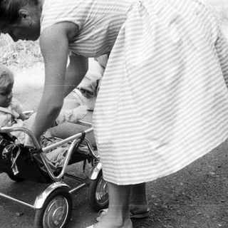 Black and white photo of a woman and child with a stroller.