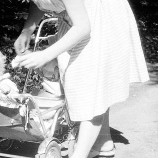 Baby in a stroller being pushed along a path.
