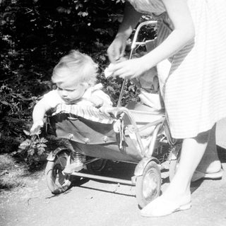Baby in a stroller being pushed along a path.
