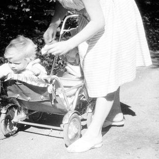 Baby in a stroller being pushed along a path.