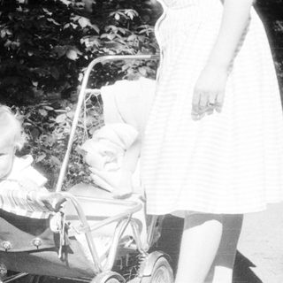 Baby in a stroller, being pushed along a path.
