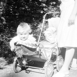 Baby in a stroller, being pushed along a path.