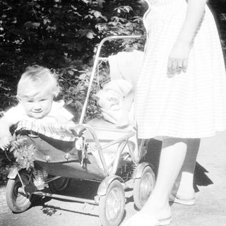 Baby in a stroller, being pushed along a path.