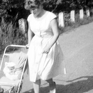 Woman pushing a baby in a vintage stroller.