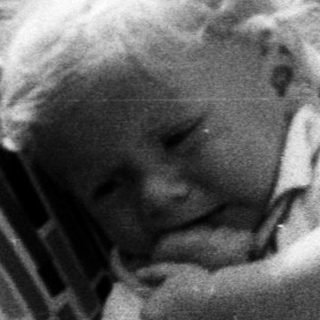 Baby in a vintage stroller, monochrome photograph.