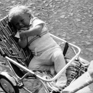 Baby in a vintage stroller, monochrome photograph.