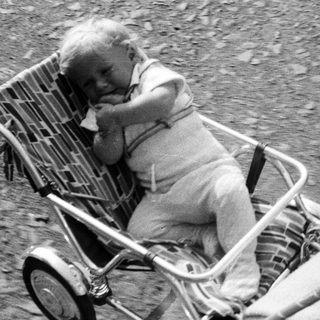 Baby in a vintage stroller, monochrome photograph.