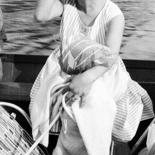 Woman sitting on a boat, appearing thoughtful or distressed.