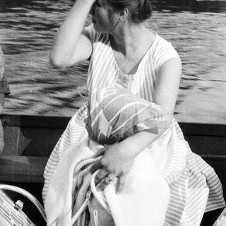 Woman sitting on a boat, appearing thoughtful or distressed.