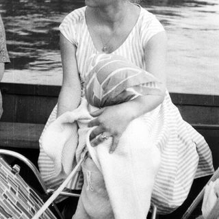 Woman holds baby while seated on a boat.