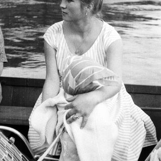 Woman holds baby while seated on a boat.