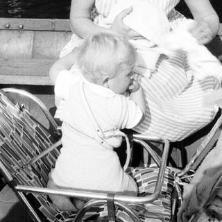 Here's a brief summary of the image: Mother breastfeeding a baby while seated on a boat.