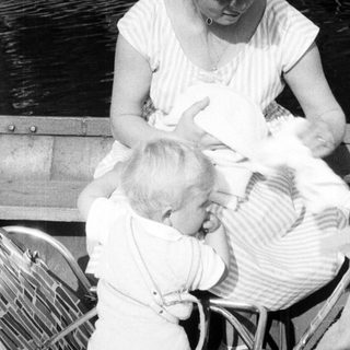 Here's a brief summary of the image: Mother breastfeeding a baby while seated on a boat.