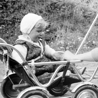 Woman with child in vintage stroller outdoors.