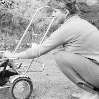 Woman with child in vintage stroller outdoors.