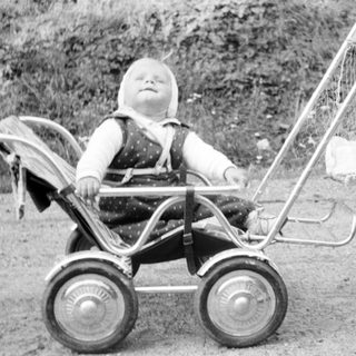 Baby in a pram with a woman nearby.