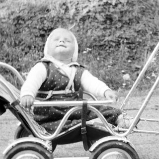 Baby in a pram with a woman nearby.