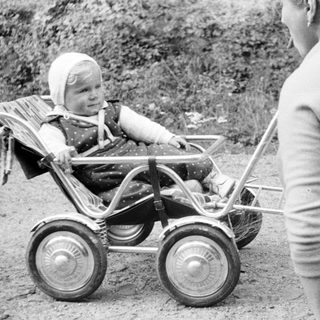 Baby in a stroller, being pushed by an adult.