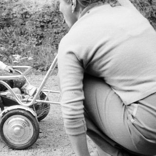 Baby in a stroller, being pushed by an adult.