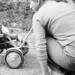 Baby in a carriage being pushed by an adult.