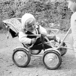 Baby in a carriage being pushed by an adult.