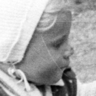 Baby in a vintage stroller, outdoors, monochrome photograph.
