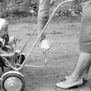 Baby in a vintage stroller, outdoors, monochrome photograph.