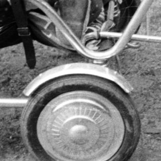 Baby in a vintage stroller, outdoors, monochrome photograph.