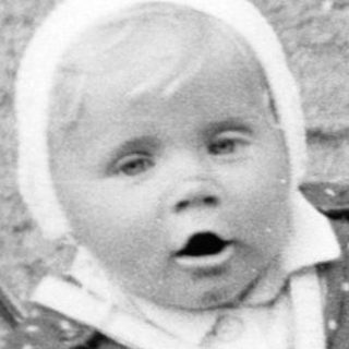 Baby in a stroller being pushed by a woman.